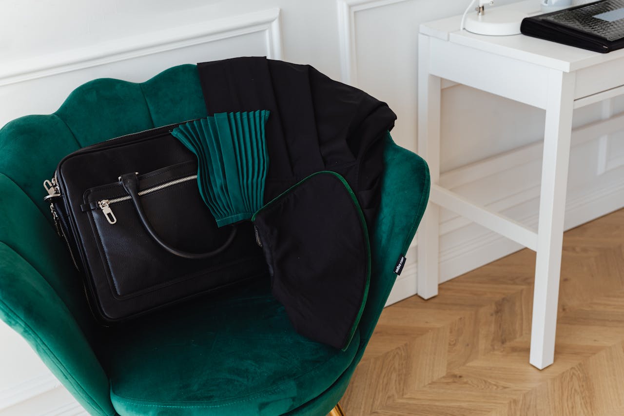 home-img Stylish green accent chair with a black handbag in a minimalist interior setting.